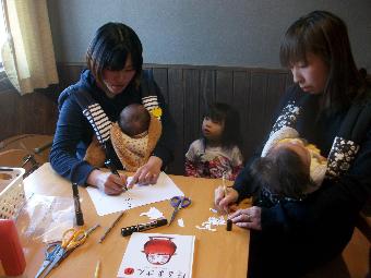 お母さんがだるまさんの顔を描く写真