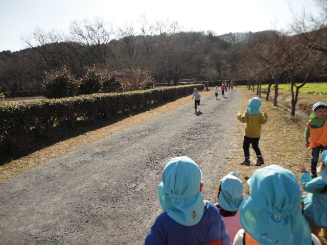 走っている5歳児を3歳児が応援している写真。