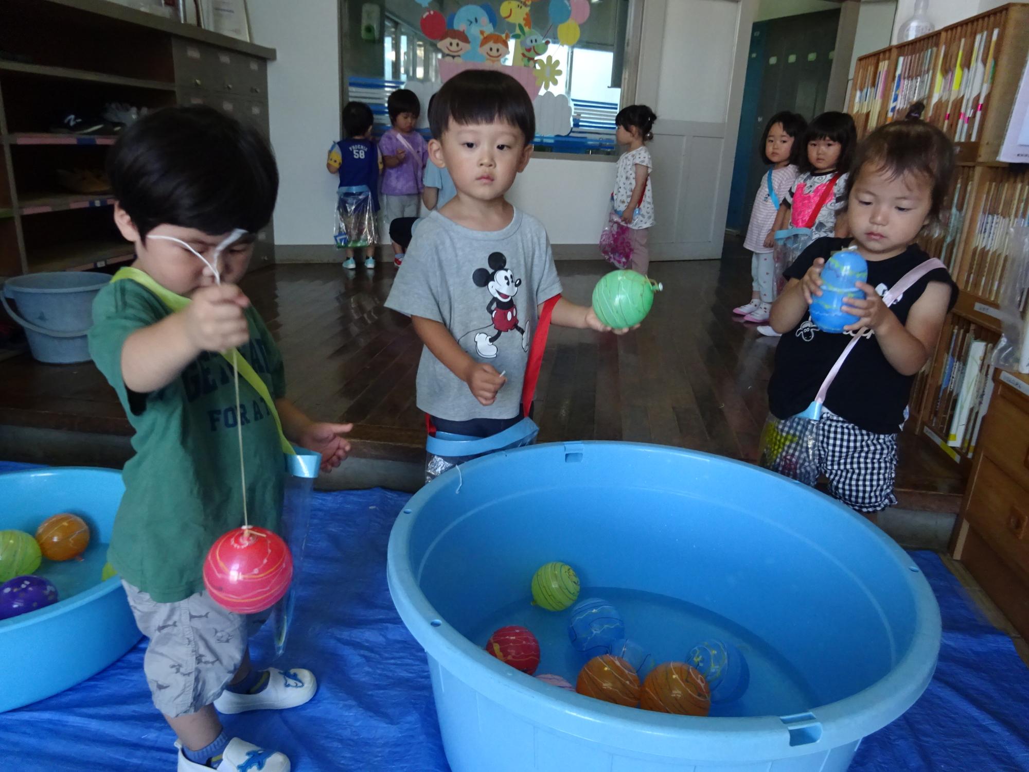 カラフルな水ヨーヨーを手に取り、興味津々の2歳児。