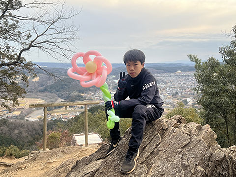 日和田山二の鳥居にある岩に腰掛けている男の子。バルーンアートを手に持っている。