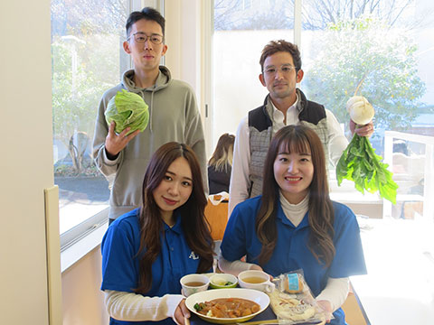 野菜を手に持った野菜の生産者と女子大生が収穫した野菜を使ってできたカレーを手にした集合写真