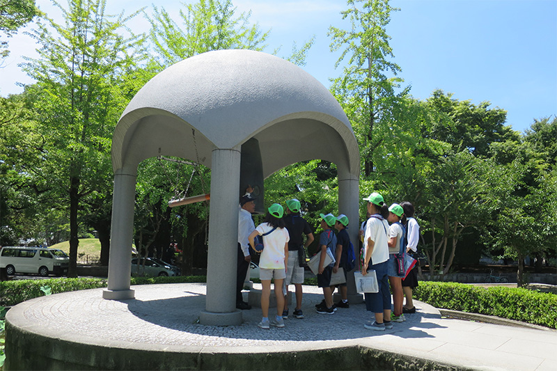 平和の鐘の下でガイドさんの説明を聞いている様子