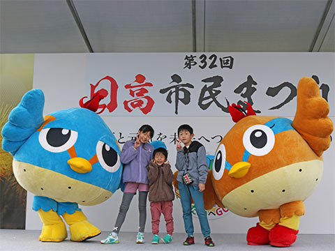 日高市民まつりのステージ上でくりっかー、くりっぴーと一緒に写真を撮る女の子1人、男の子2人