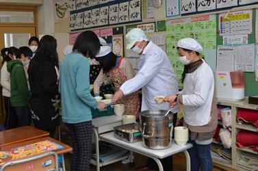 児童と一緒に給食の配膳をしている市長の写真