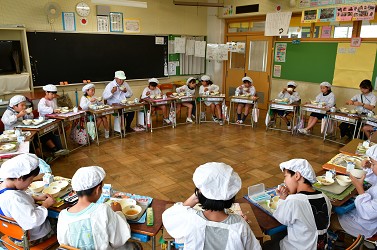 輪になって給食を食べている写真