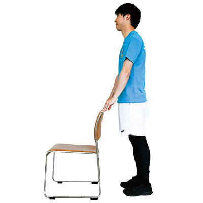 いすを正面に軽く支えて立っている写真