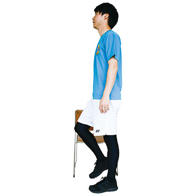 いすを軽く支え片足を軽く上げている写真