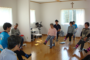 椅子に座った状態でおもりをつけた片足をあげている様子