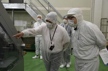 製品を箱詰めする機械を見学している写真