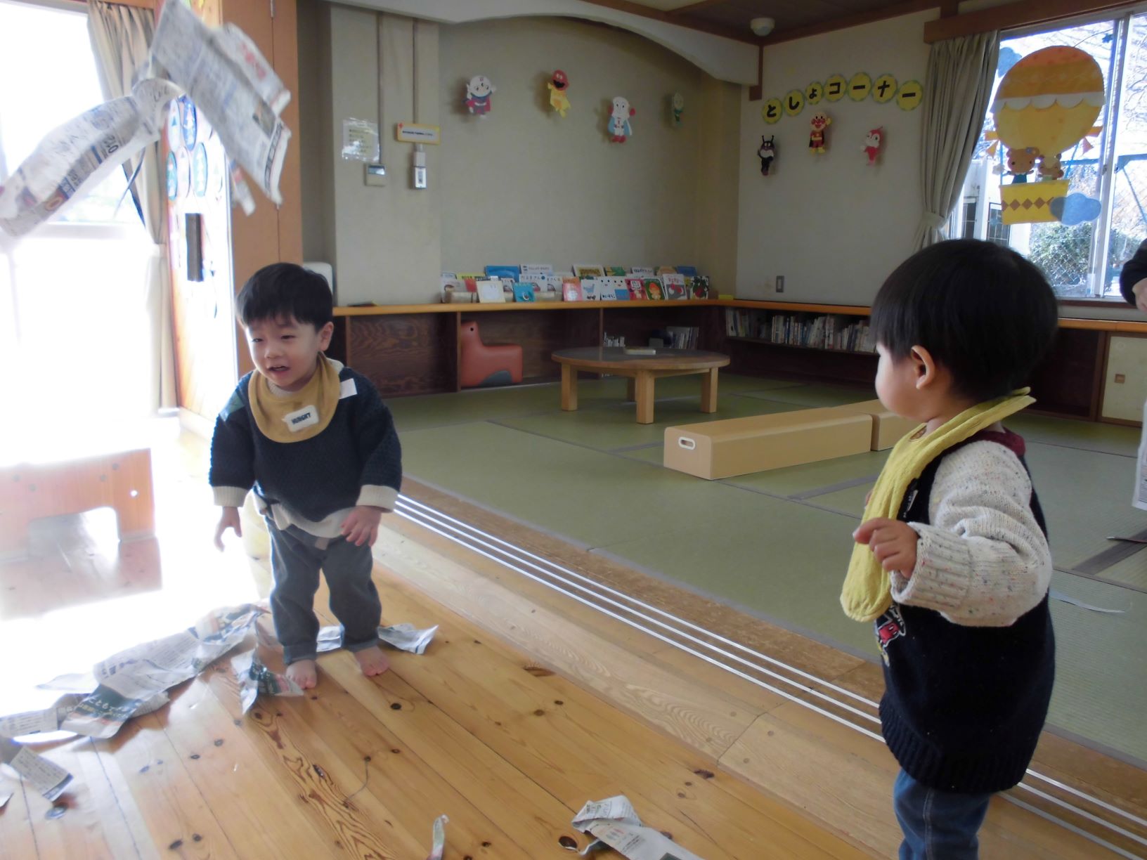 ちぎった新聞紙を投げて遊ぶ子どもたち