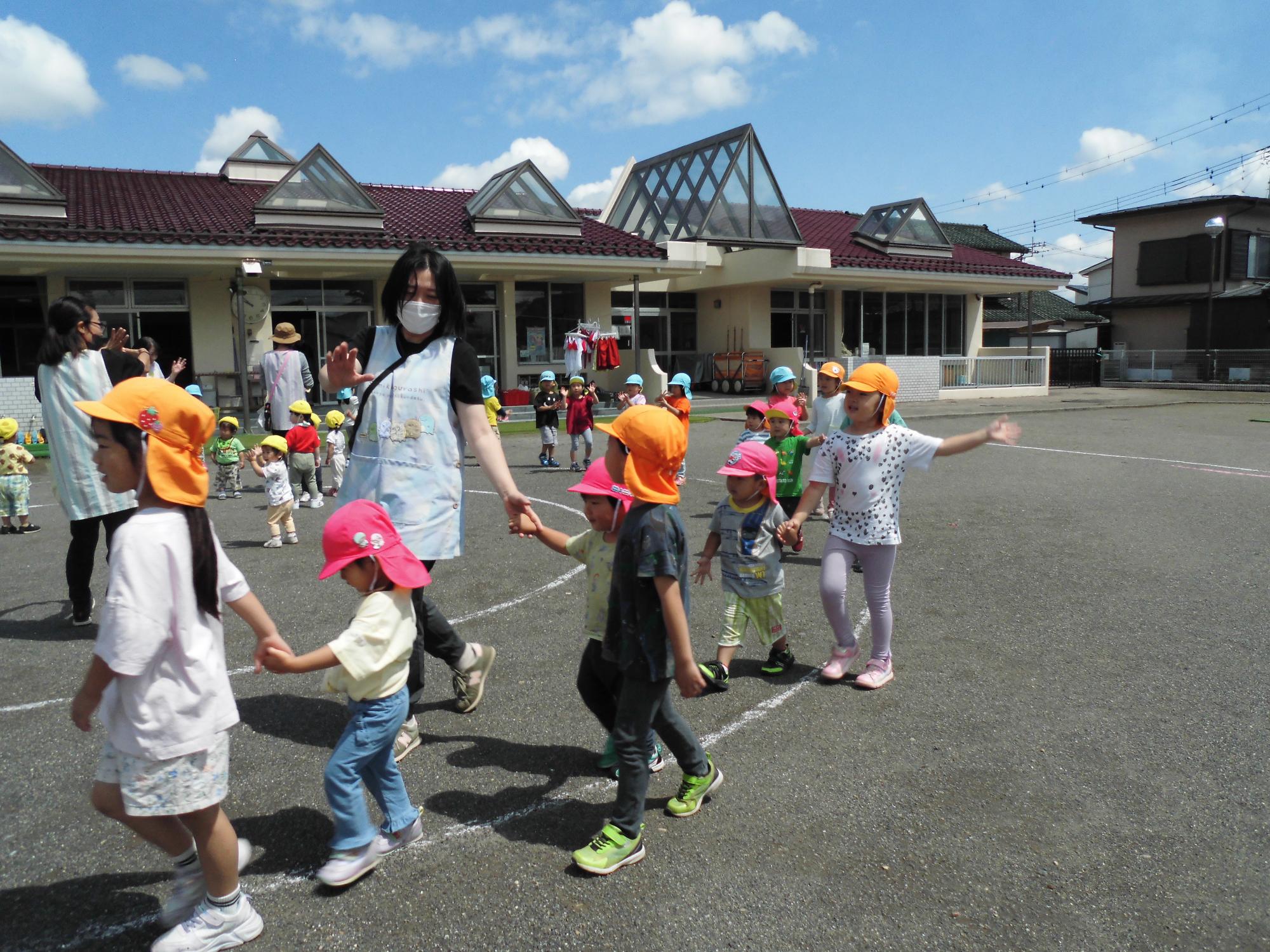 大きいクラスのお友達が小さいクラスのお友達の手を引いて入場しているところ