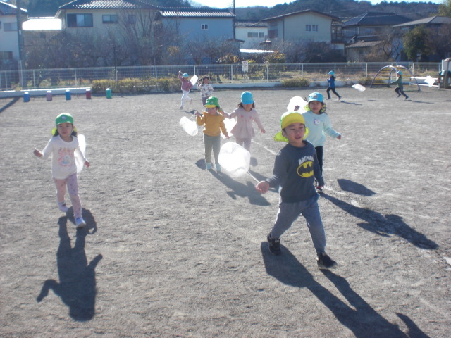 園庭を思い切り走ってたこをあげる様子