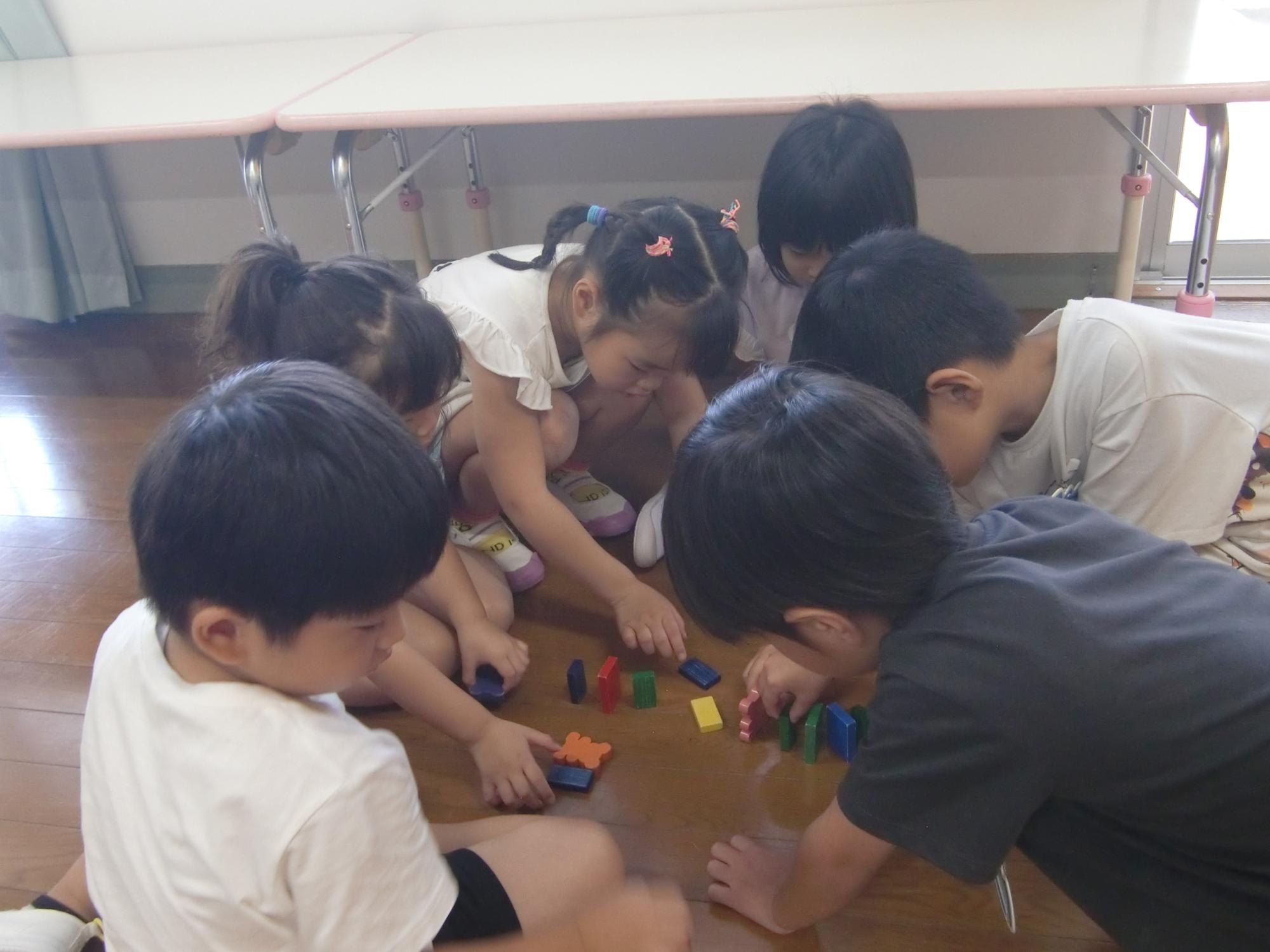 異年齢児が声を掛け合ってドミノをしている様子