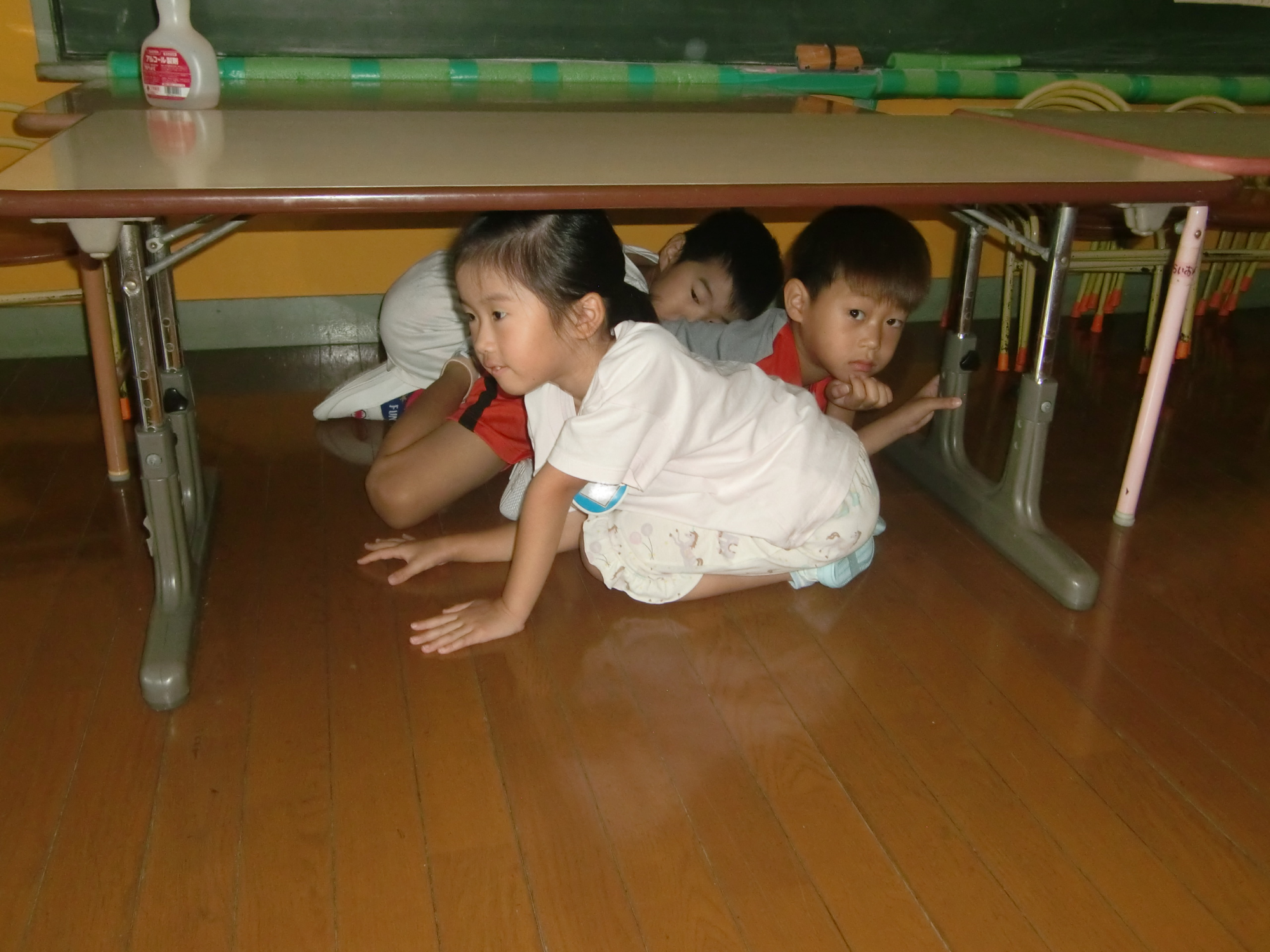 子どもたちが異常を察知し、机の下に隠れている