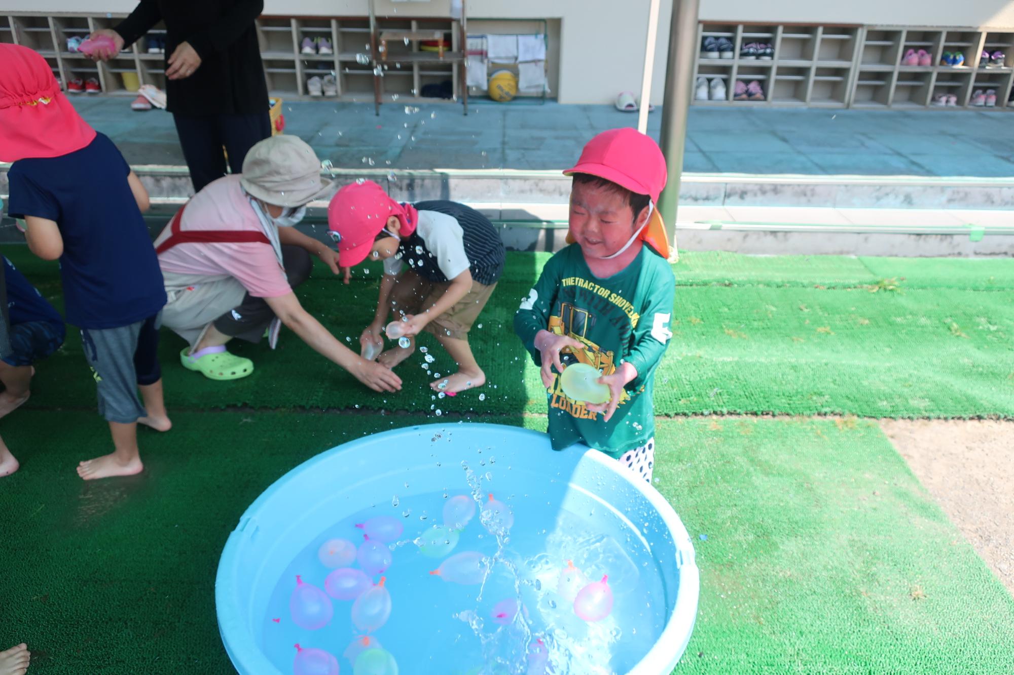タライに水風船を落として楽しむ子ども