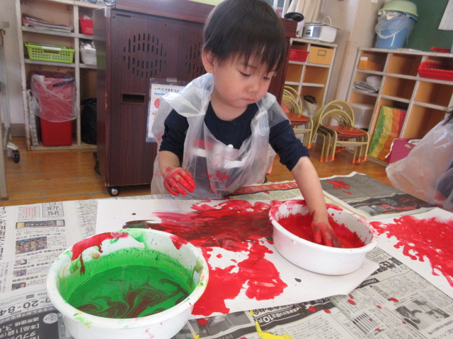 赤の絵の具を大胆に手で塗っています