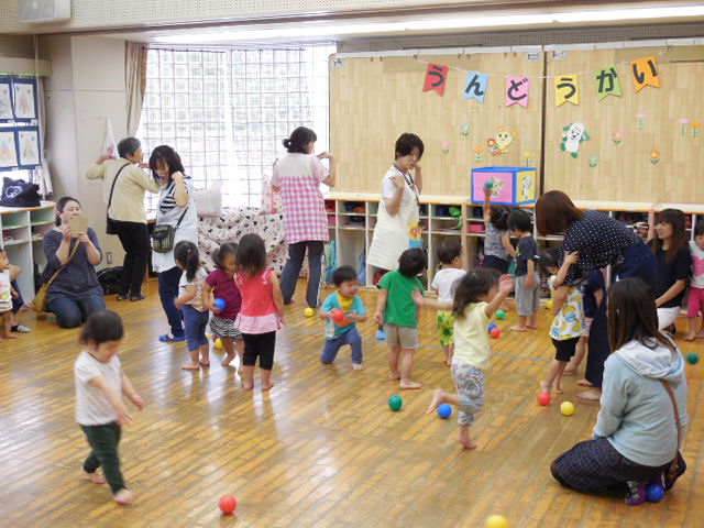 音楽に合わせて玉入れをしている2歳児