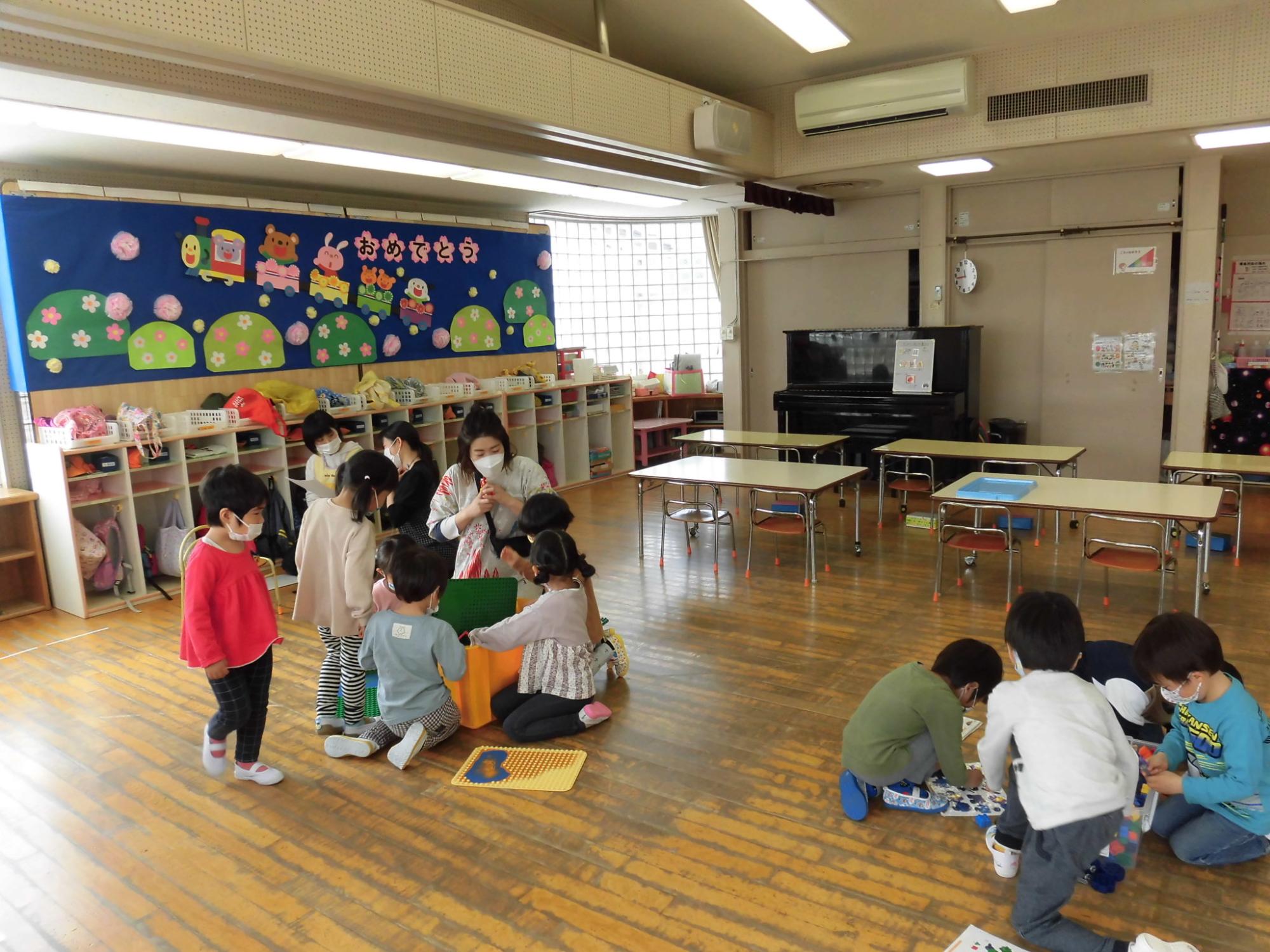 年中児がおめでとうと書かれた壁面装飾の前で遊んでいるところ