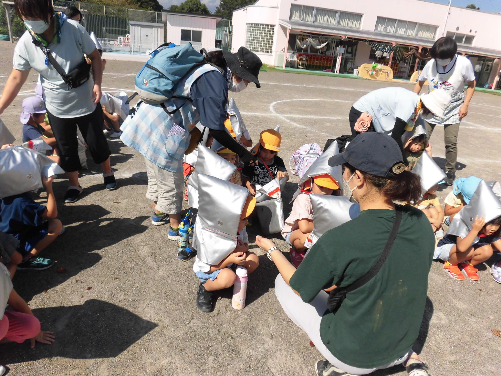 避難訓練で幼児が防災頭巾をかぶる練習をしているところ