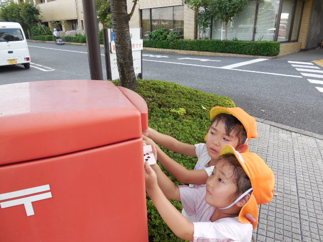 はがきをポストに投函している写真