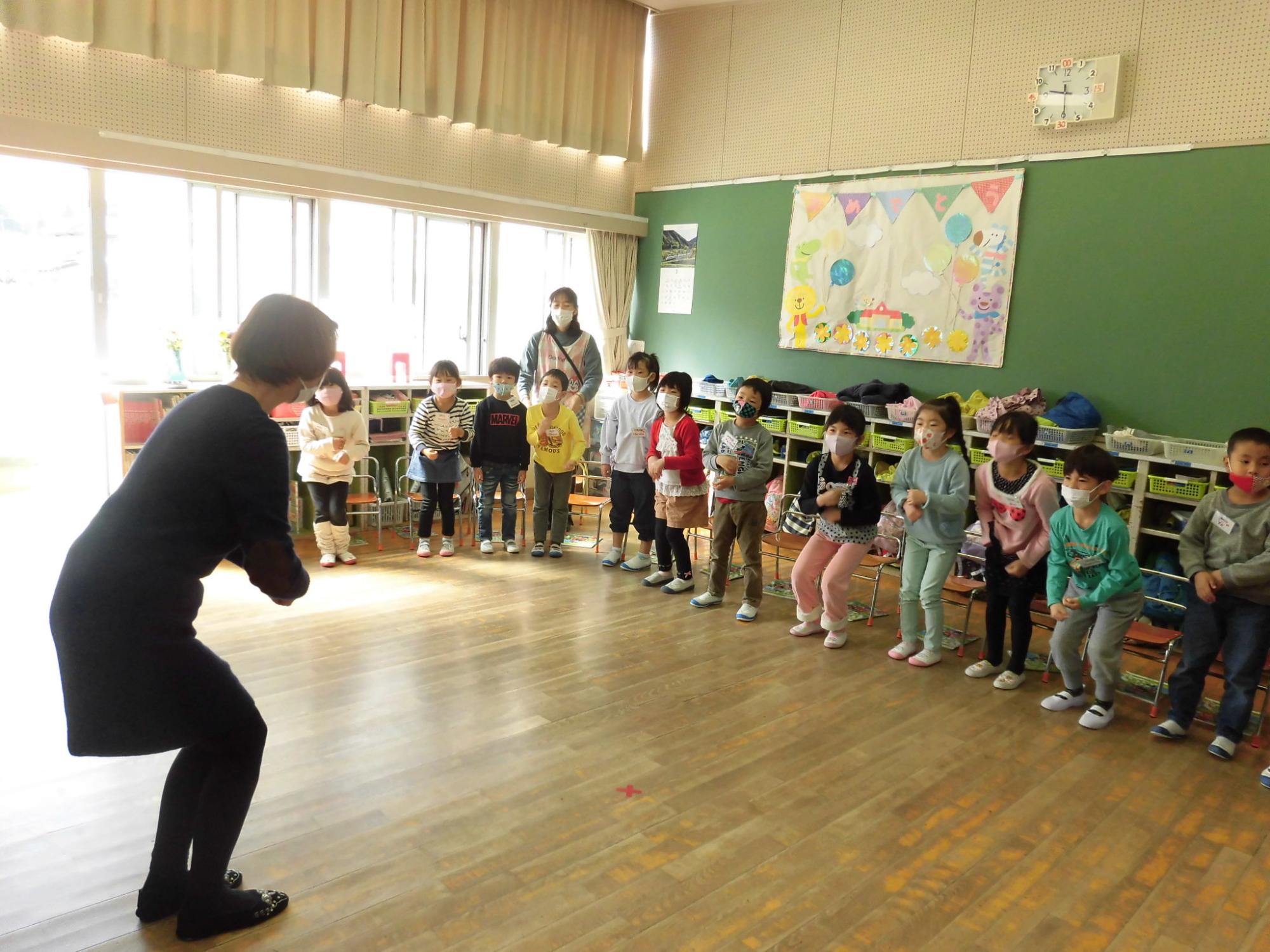 ジェスチャーを交えて子どもたちに教えている写真。