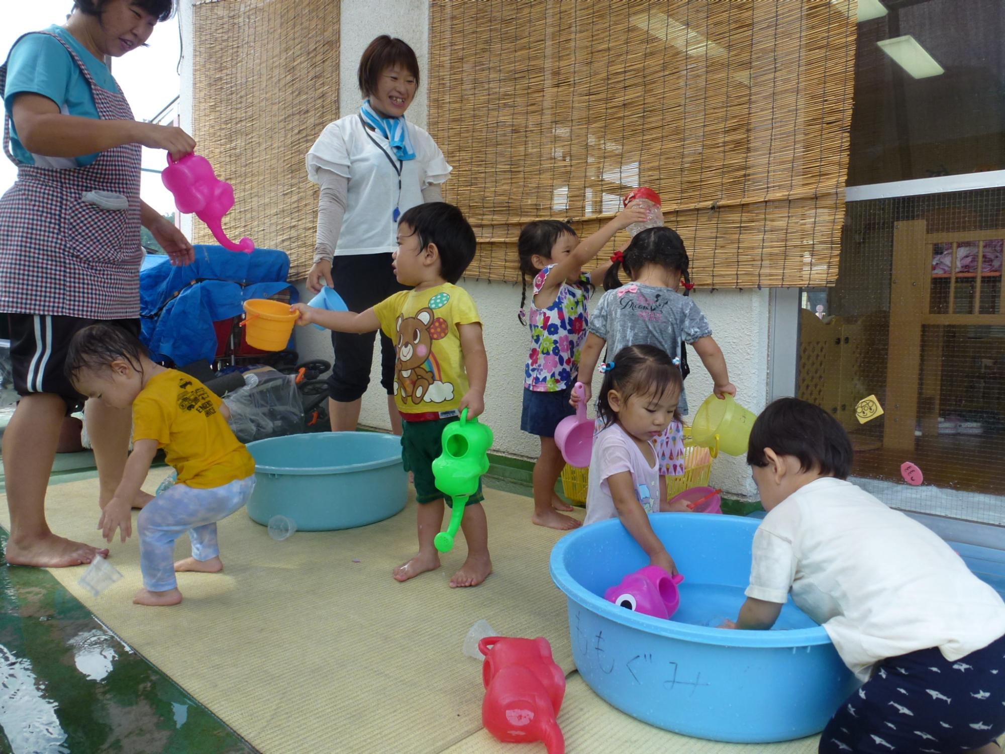 タライに水を張り、水遊びをする1,2歳児
