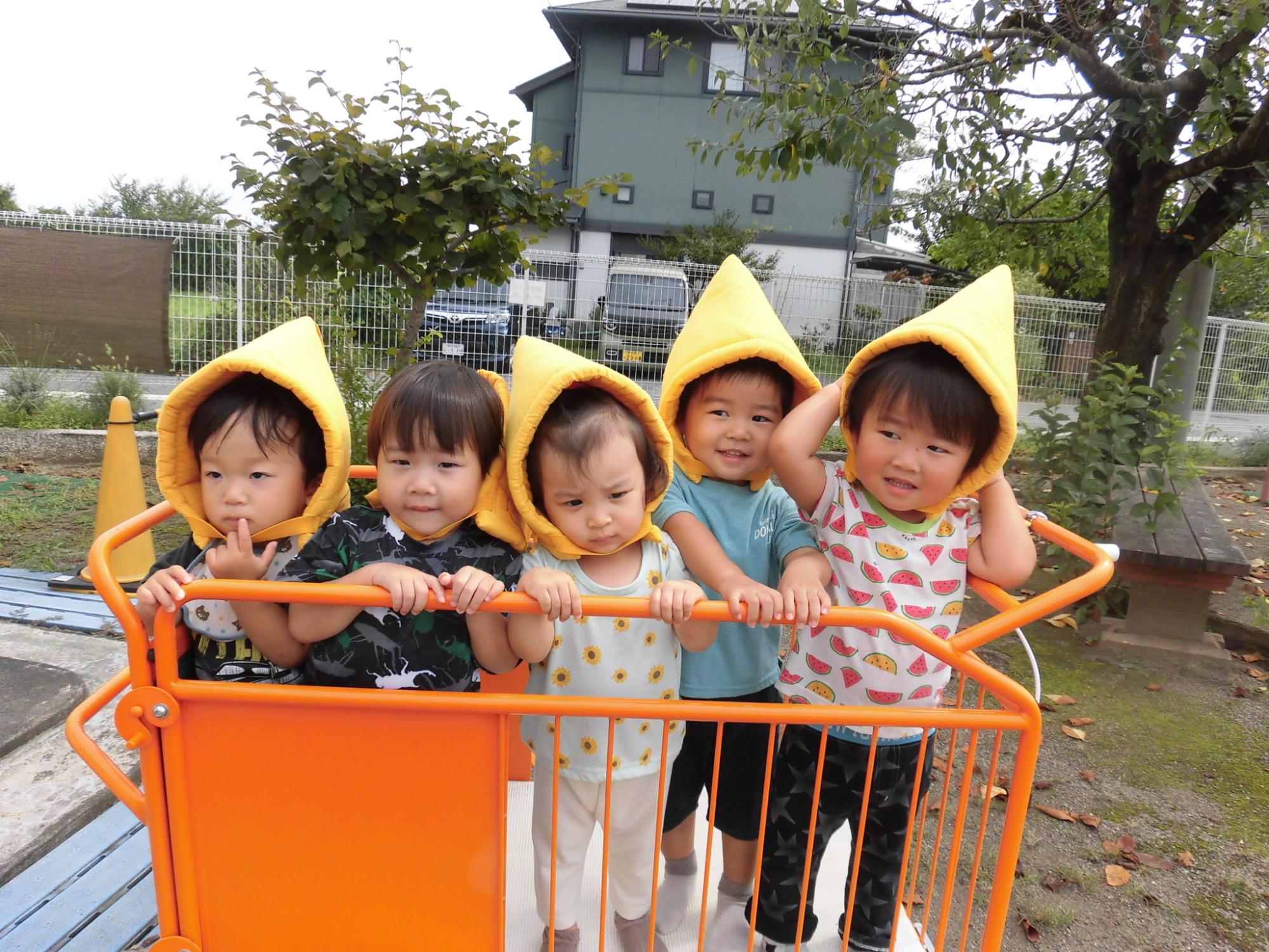 1歳児が避難車に乗り、防災頭巾をかぶる訓練をしているところ