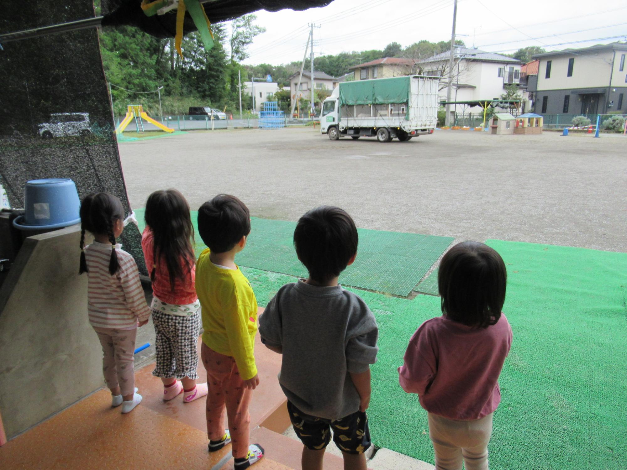 動物が乗ったトラックを見送る子どもたちの後ろ姿