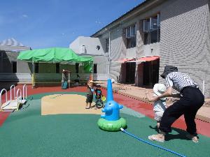 スプリンクラーの水で遊ぶ子ども