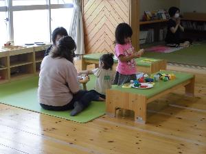 ヨガをする親と同じ部屋で遊ぶ子どもたち