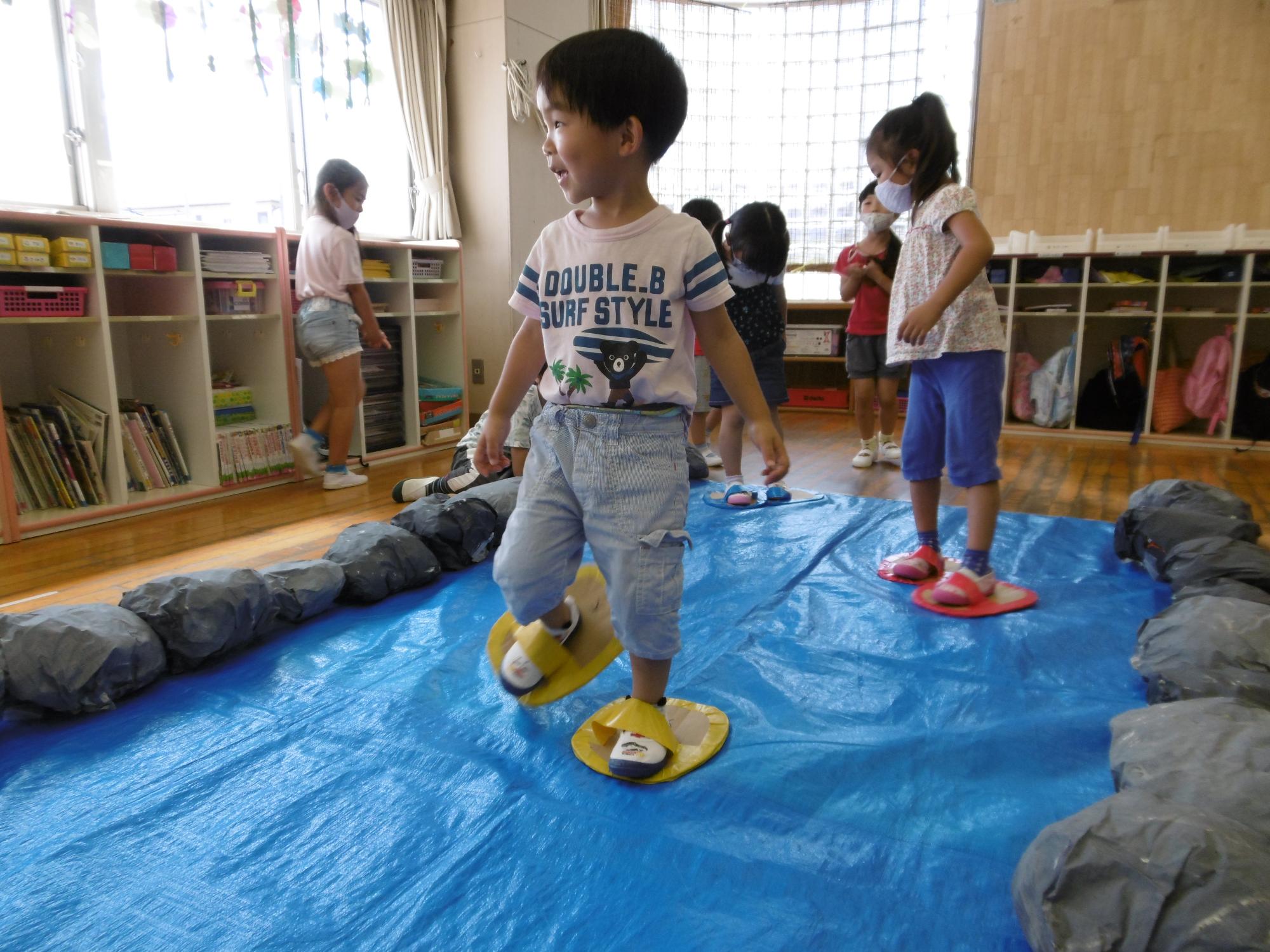 年少児が草履をはいて池渡りの忍者修行をしている写真