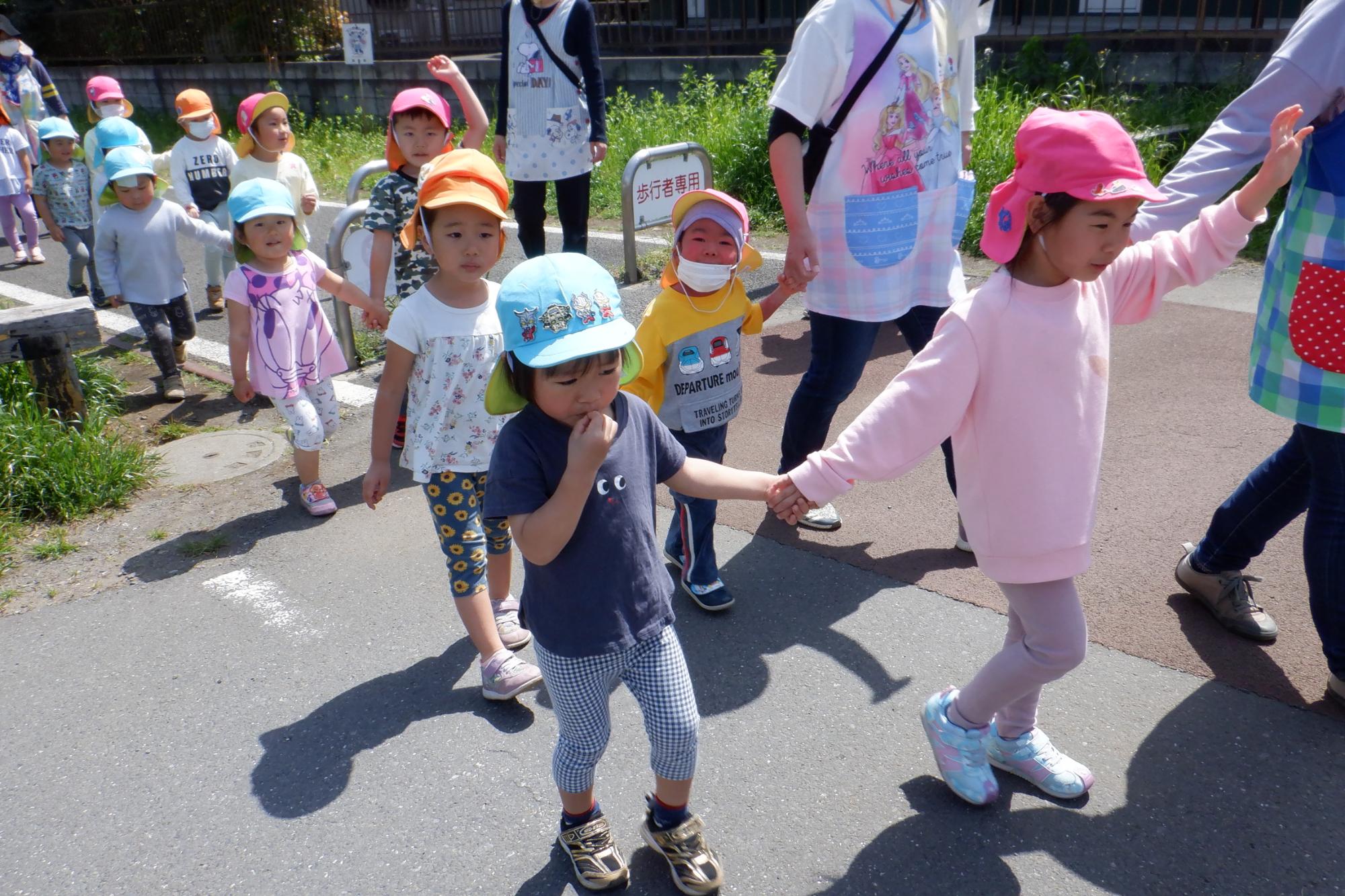 手をつないで手を上げて道を横断する子どもたち