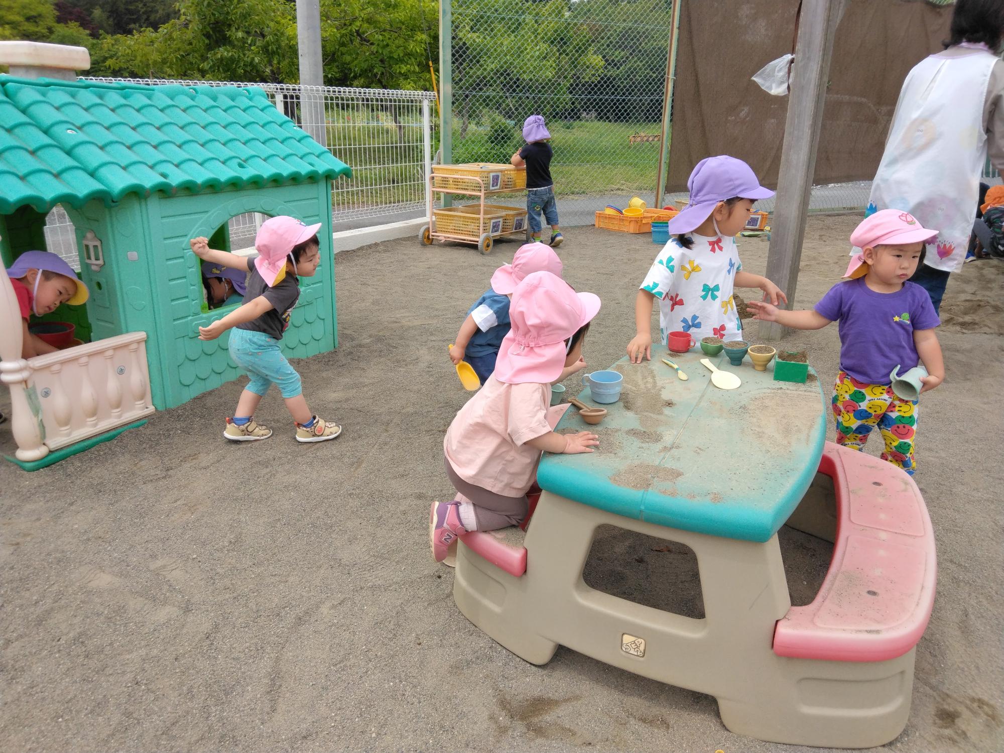 砂場で遊んでいる1歳児と4歳児