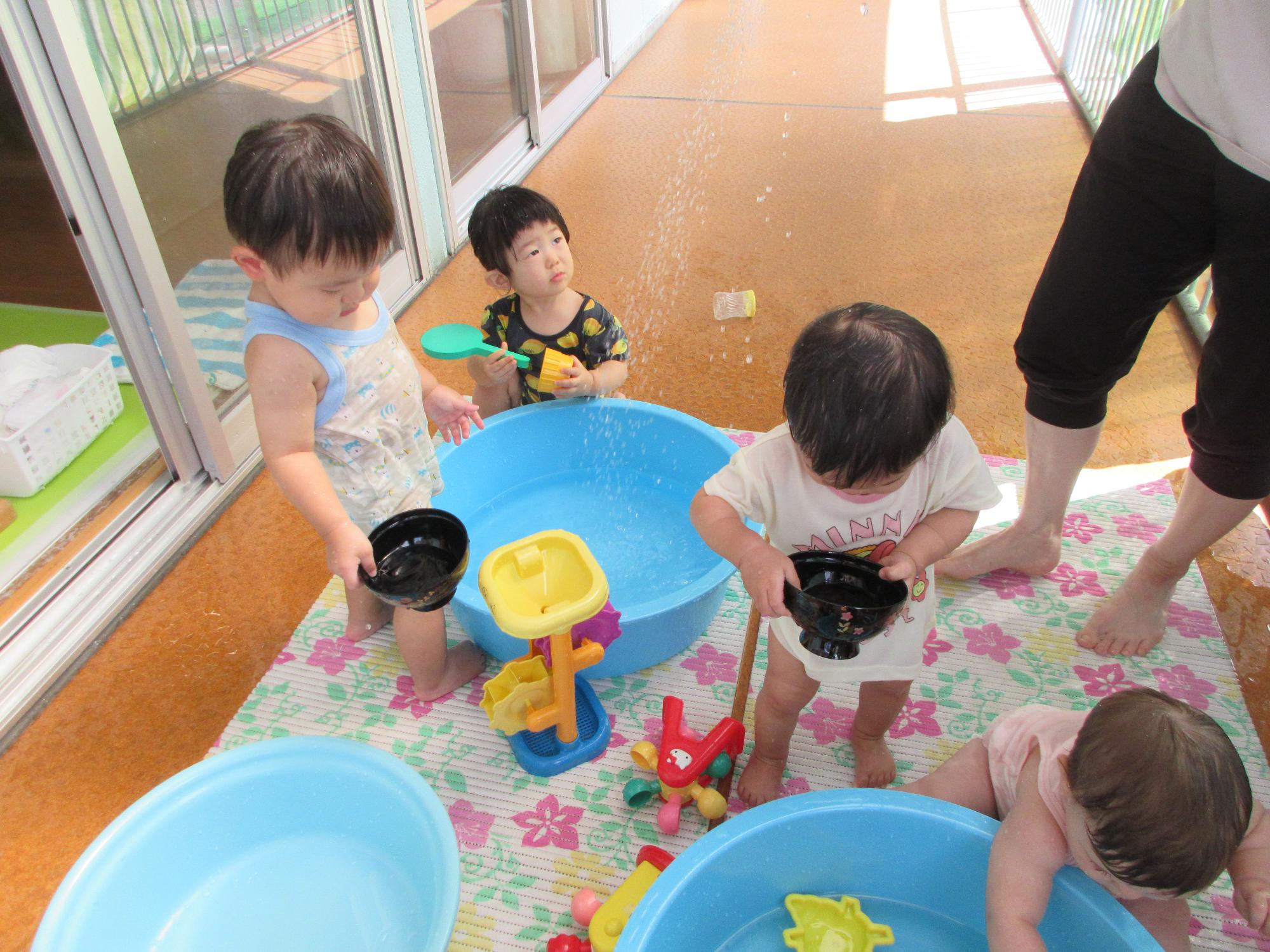タライに水をためておわんで水をすくって遊んでいるところ