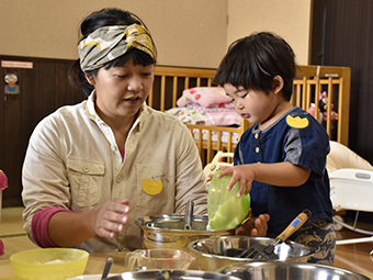 材料をボウルに入れる子どもとそれを見守るお母さん