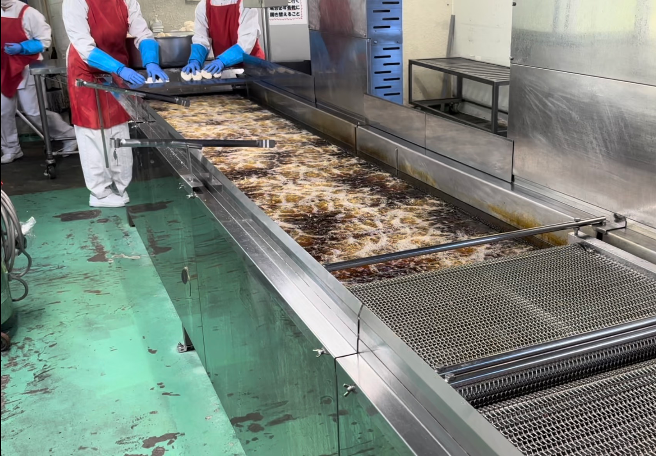 大型の揚げ物機で調理をしている写真