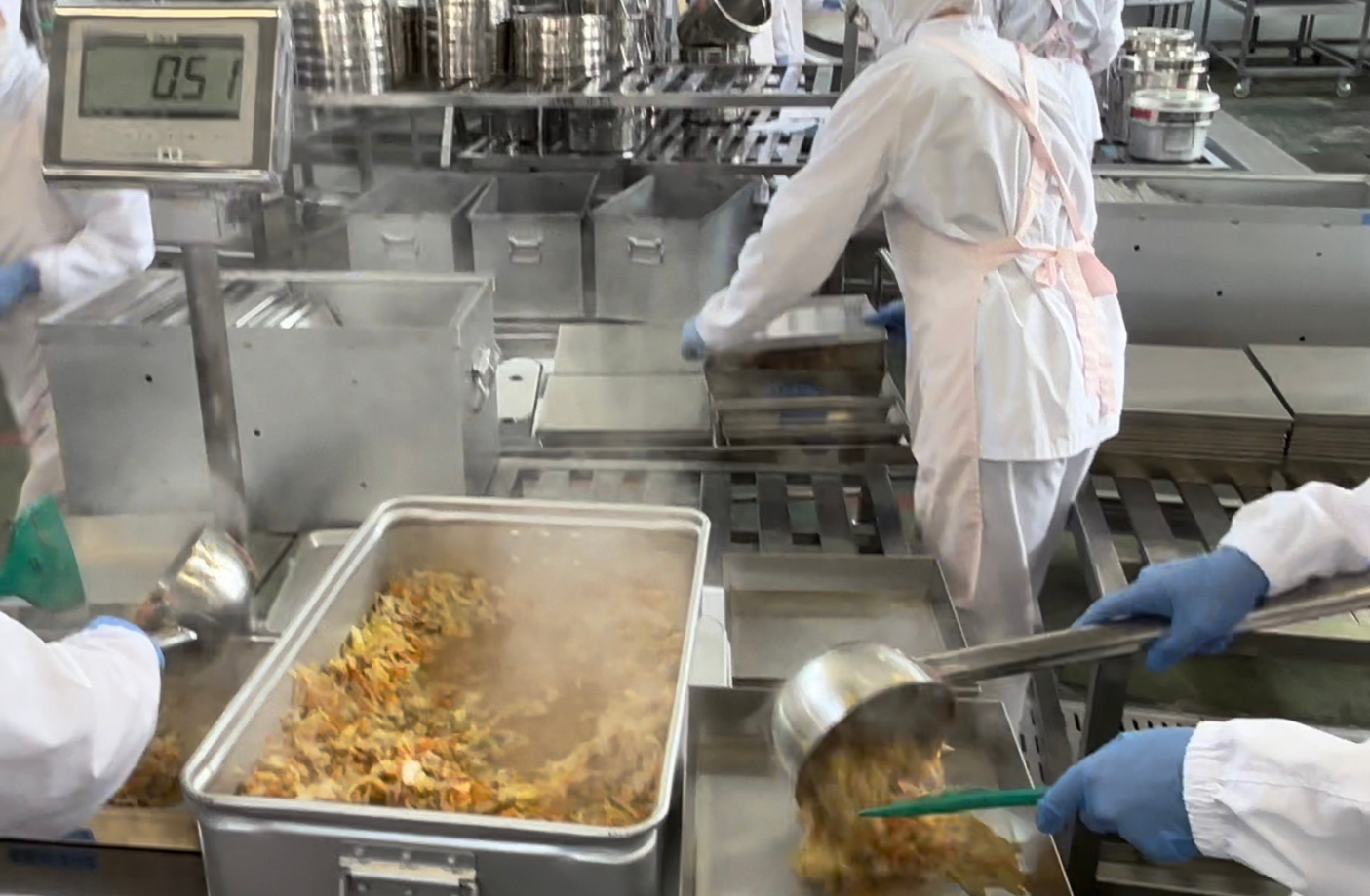 できあがった料理を、各クラスの食缶に配分している写真