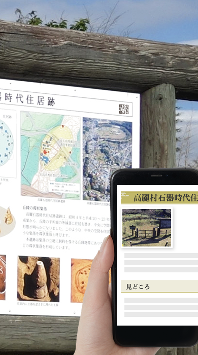 高麗村石器時代住居跡の説明板のQRをスマートフォンで読み込み、スマートフォンに高麗村石器時代住居跡の説明書きが表示されている様子