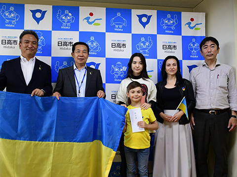 ウクライナ国旗を持つ三成研機株式会社の社長と日高市長とウクライナの子どもとその家族