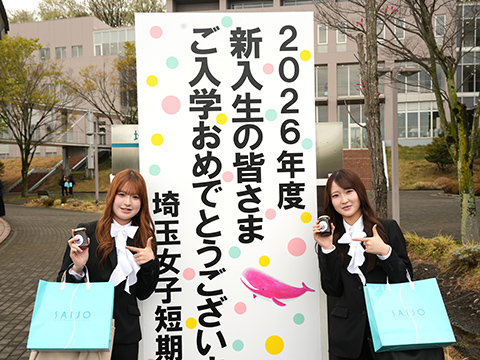 入学式の看板の前で記念写真を取る2人の学生