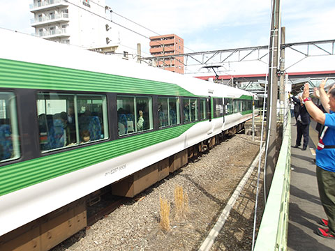 ホームから手を振って見送る人と電車内から手を振り返してくれている乗客