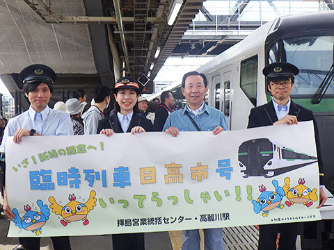 市長とJR高麗川駅職員が笑顔で記念プラカードを持っている いざ！新緑の鎌倉へ！臨時列車日高市号いってらっしゃい！！拝島営業統括センター・高麗川駅