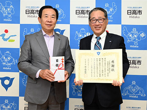 感謝状を手に市長と記念撮影する日高都市ガス株式会社社長塚越さん