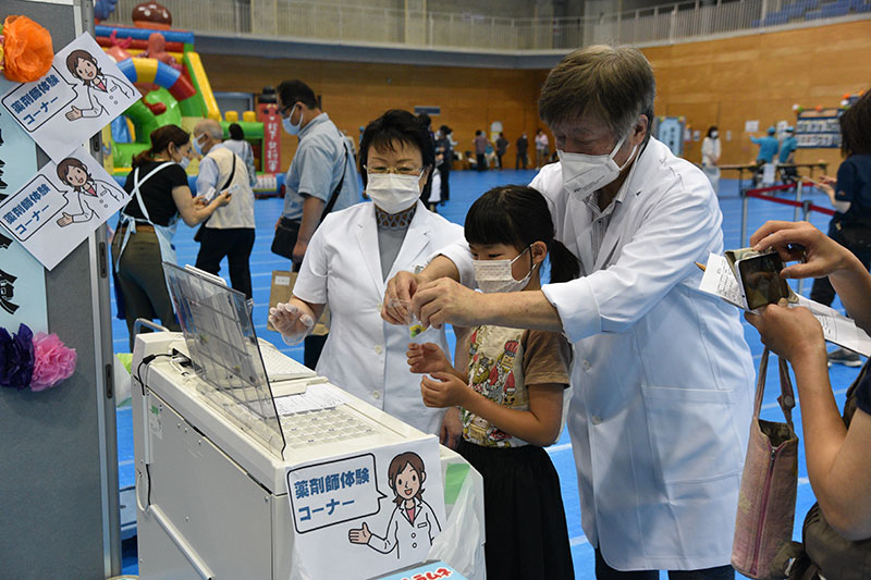 タブレットのようなものを機械に入れて薬剤師体験している様子