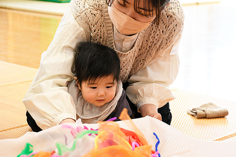 布に興味を持っている子どもを見守るお母さんの様子