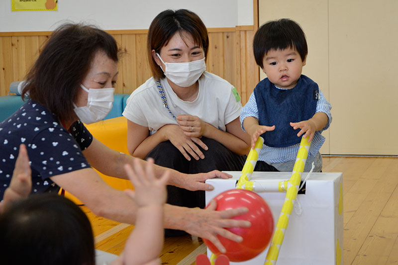 梯子状のスロープにボールを転がして遊ぶ子どもの様子