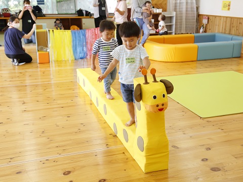 キリンの遊具の背中を渡る子どもたちの写真