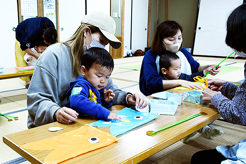 親子で一緒にこいのぼりの鱗を貼る様子