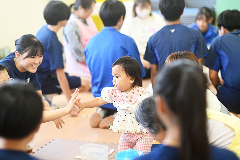 赤ちゃんを手でタッチする生徒