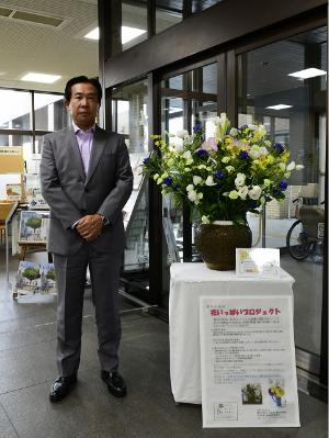 市役所入口に展示している「埼玉県花いっぱい活動」の花飾りと谷ケ崎市長の写真